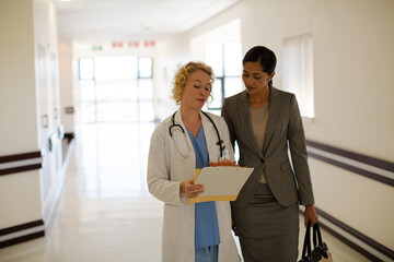 Doctor and businesswoman walking in hospital corridor