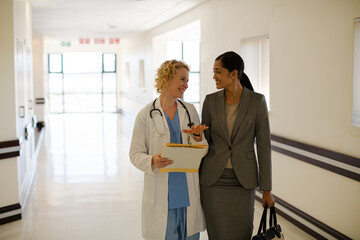 Doctor and businesswoman walking in hospital corridor