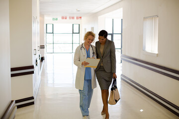 Doctor and businesswoman walking in hospital corridor