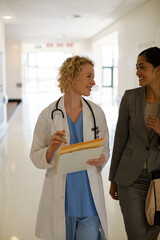 Doctor and businesswoman walking in hospital corridor