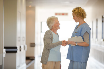 Obraz premium Nurse and senior patient shaking hands in hospital corridor