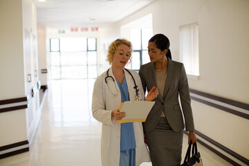 Doctor and businesswoman walking in hospital corridor