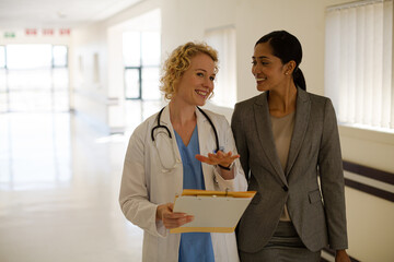Fototapeta premium Doctor and businesswoman walking in hospital corridor