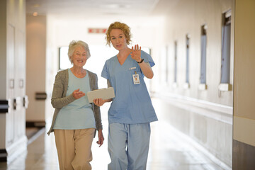 Obraz premium Nurse and senior patient talking in hospital corridor