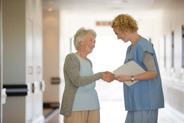 Obraz premium Nurse and senior patient shaking hands in hospital corridor