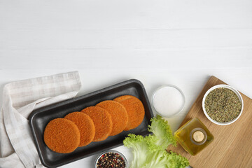 Uncooked breaded cutlets on white wooden table, flat lay. Freshly frozen semi-finished product