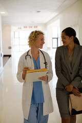 Doctor and businesswoman walking in hospital corridor