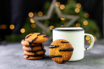 orange cookies with black stripes and cup of tea with fir tree branch. Christmas dessert. Concept...