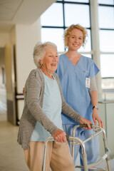 Nurse helping senior patient with walker in hospital corridor