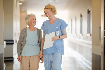 Obraz premium Nurse and senior patient talking in hospital corridor