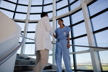 Doctor and nurse handshaking on hospital staircase