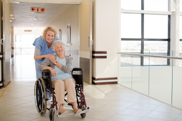 Portrait of smiling nurse and elderly patient in wheelchair