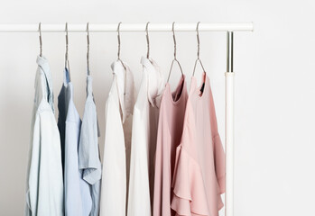 Women's casual clothes in soft pastel colors on a gray metal hanger on a stand, hanger. T-shirts, shirts, blouses pink, blue, white. General cleaning and organization of space, spring