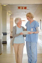 Fototapeta premium Nurse and aging patient reading chart in hospital corridor