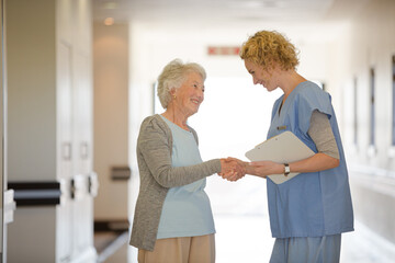 Obraz premium Nurse and senior patient shaking hands in hospital corridor
