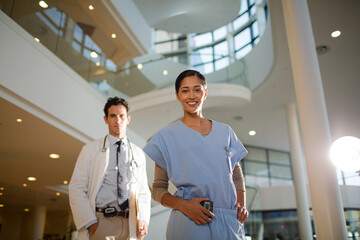 Obraz premium Portrait of smiling doctor and nurse in hospital atrium