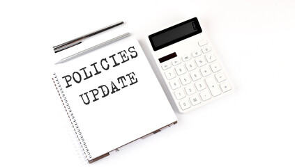 Notepad with text POLICIES UPDATE with calculator and pen. White background. Business concept