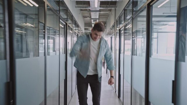Excited man showing yes gesture walking in office hall, successful business deal