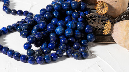 Beautiful bright  round blue lapis lazuli beads close up on a white background. Vintage composition.