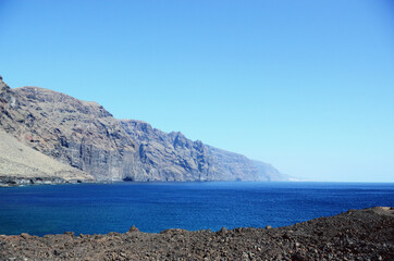 Fototapeta premium TENERIFE, SPAIN: Scenic seashore view of Los Gigantes ancient rocks with blue sea waters