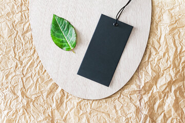 Clothing tag and green leaf as eco-friendly flatlay background, sustainable fashion and brand label...