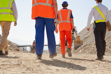 Workers and businessman talking by car in quarry