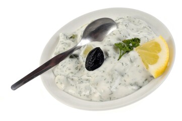 Assiette de tzatziki avec un olive noire et une cuillère en gros plan sur fond blanc