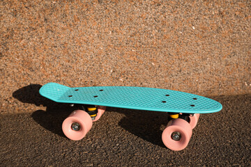 Light blue skateboard with pink wheels on asphalt outdoors