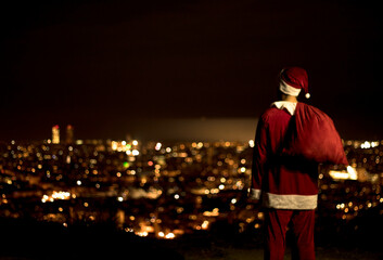 Papa Noel de espaldas mirando la ciudad de noche
