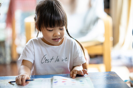 A cute 3-year-old Asian girl is practicing writing. It is an image that focuses on the subject behind blur. concept of hand muscle training