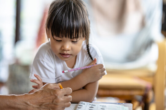 A cute 3-year-old Asian girl is practicing writing and reading. It is an image that focuses on the subject behind blur. concept of hand muscle training