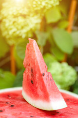 Triangular slice of juicy ripe watermelon on half watermelon. Concept of healthy delicious food in...