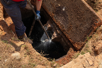 Man breaking apart a wastewater outlet in an old septic tank to bring it up to code, horizontal...