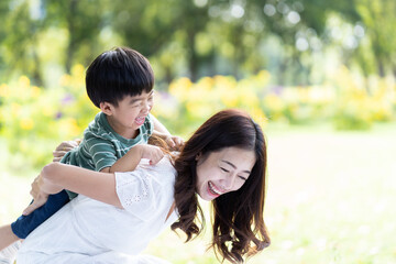 Happy Asian family playing together outdoor. Cheerful mother and little son having fun and relaxing on holiday in the the park. Mom spending time with little son on vacation. Happy family and holiday