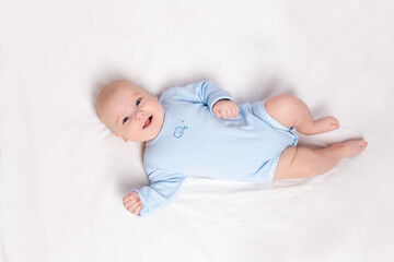 happy baby lies in the crib, cute little boy of six months lies in the nursery on the bed