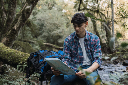 Traveling Man Reading Paper Map In Forest