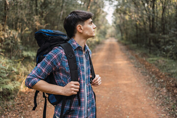 Traveler with backpack walking along road in woods