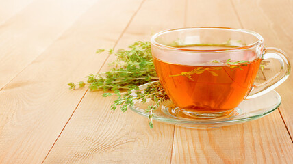 mug of hot tea with fresh thyme on a wooden table