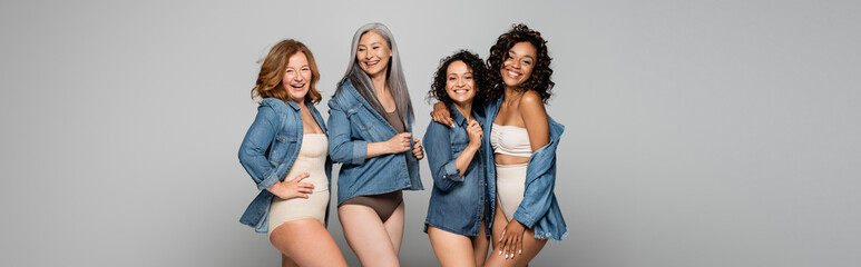 Positive multiethnic women in lingerie and denim shirts isolated on grey, banner