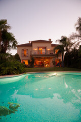 Luxury swimming pool and villa at dusk