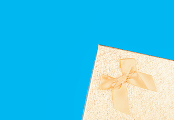 The edge of a gift box with a fabric bow on a blue background.