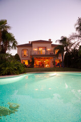 Luxury swimming pool and villa at dusk