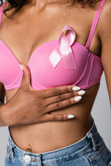 Cropped view of african american woman with pink ribbon on bra isolated on grey