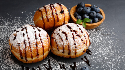 Donut or bun made from sweet yeast dough with chocolate sauce and sprinkled with powdered sugar.
