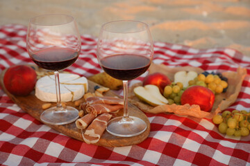 Blanket with wine and snacks for picnic on sandy beach