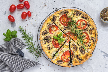 Whole homemade vegetable tart with mushrooms, tomatoes and zucchini on white background, top view