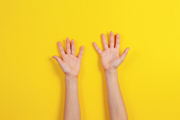 Two kid arms on yellow background. Top view to empty opened palms up. Hands gesture