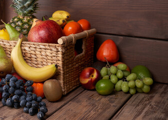 Mix of fresh juicy colorful exotic tropical fruits in basket on wooden background