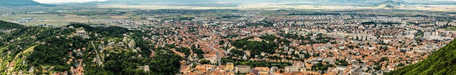 Fototapeta na wymiar Aerial panoramic view of Brasov surrounded by the Carpathian mountains dotted with ski resorts including the ever popular Boiana Brasov. Romania, the Balkans, Eastern Europe