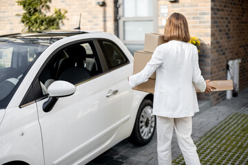 Woman with parcels near her car and home